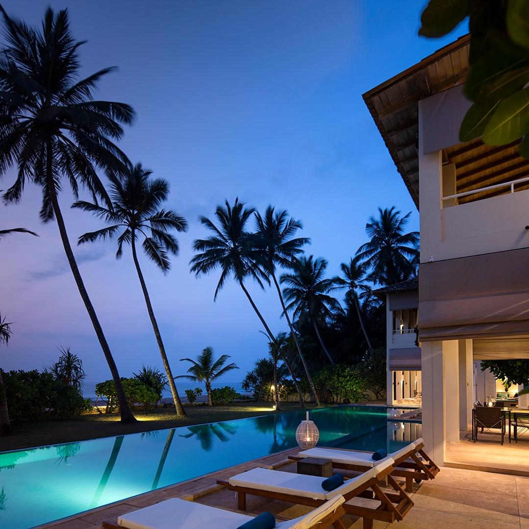 Sri Villas Induruwa pool and palm trees illuminated at dusk, Induruwa Sri Lanka