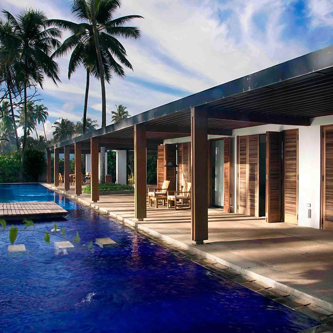 Villa Maggona open pool pavilion with swaying palm trees and blue tropical sky