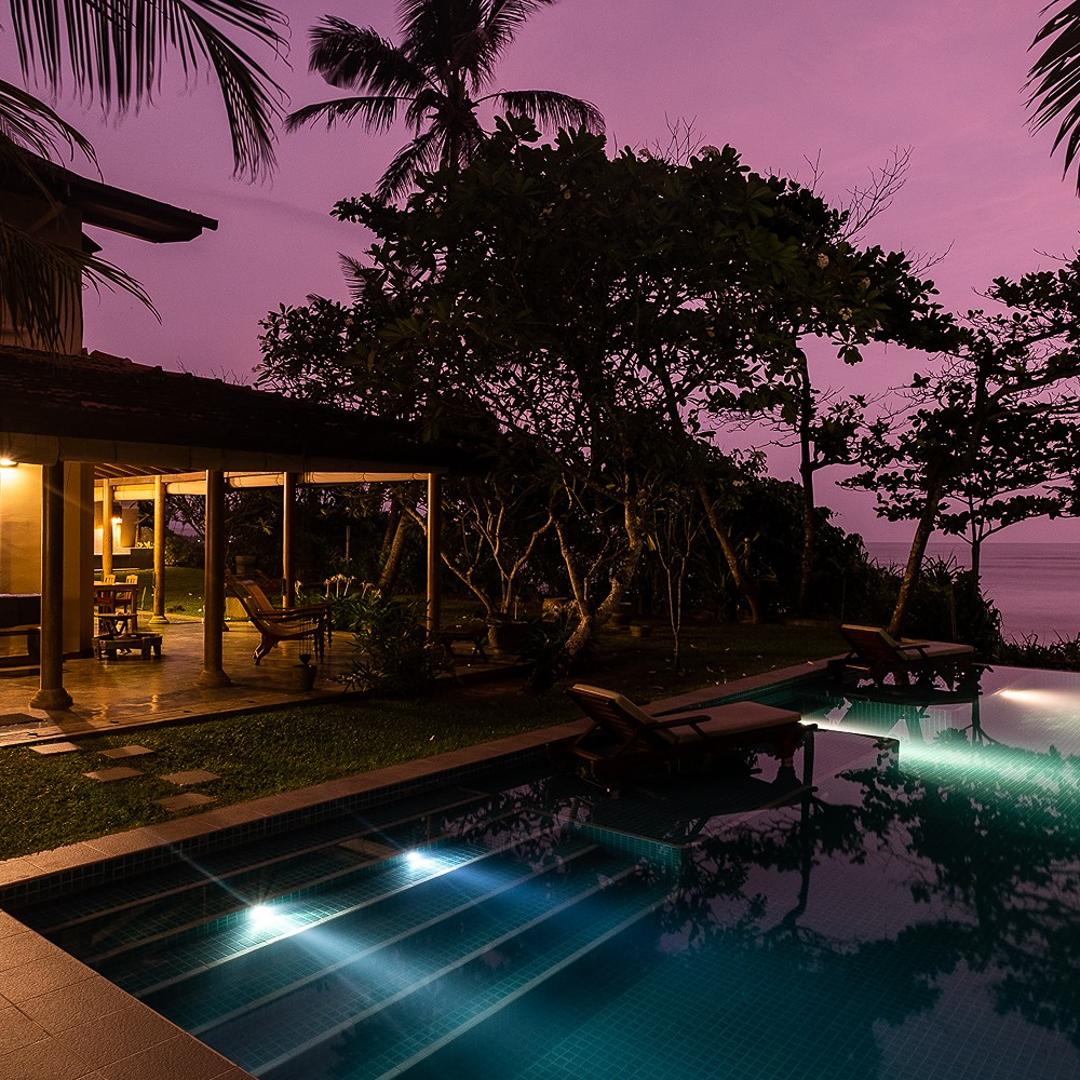 Villa Tres Matara infinity pool illuminated at evening with pink sky
