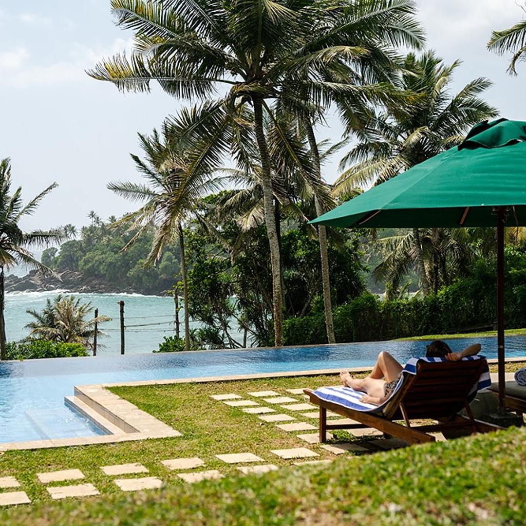 Wide-angle view of the expansive garden at Pavana Hiriketiya with towering palm trees and manicured lawn