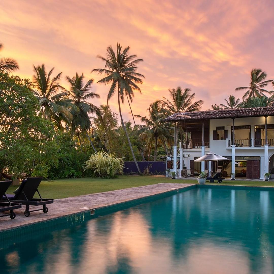 Sun loungers beside the pool at dusk with the illuminated villa facade at Casa Lago, Koggala