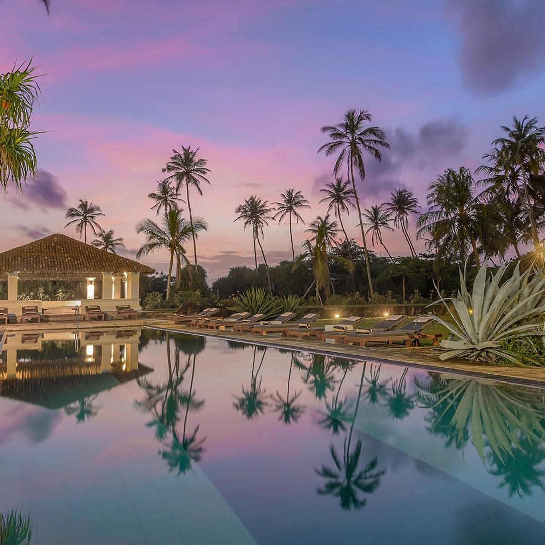 Heritage House Bentota pool at dusk under a vivid purple sky with palm silhouettes