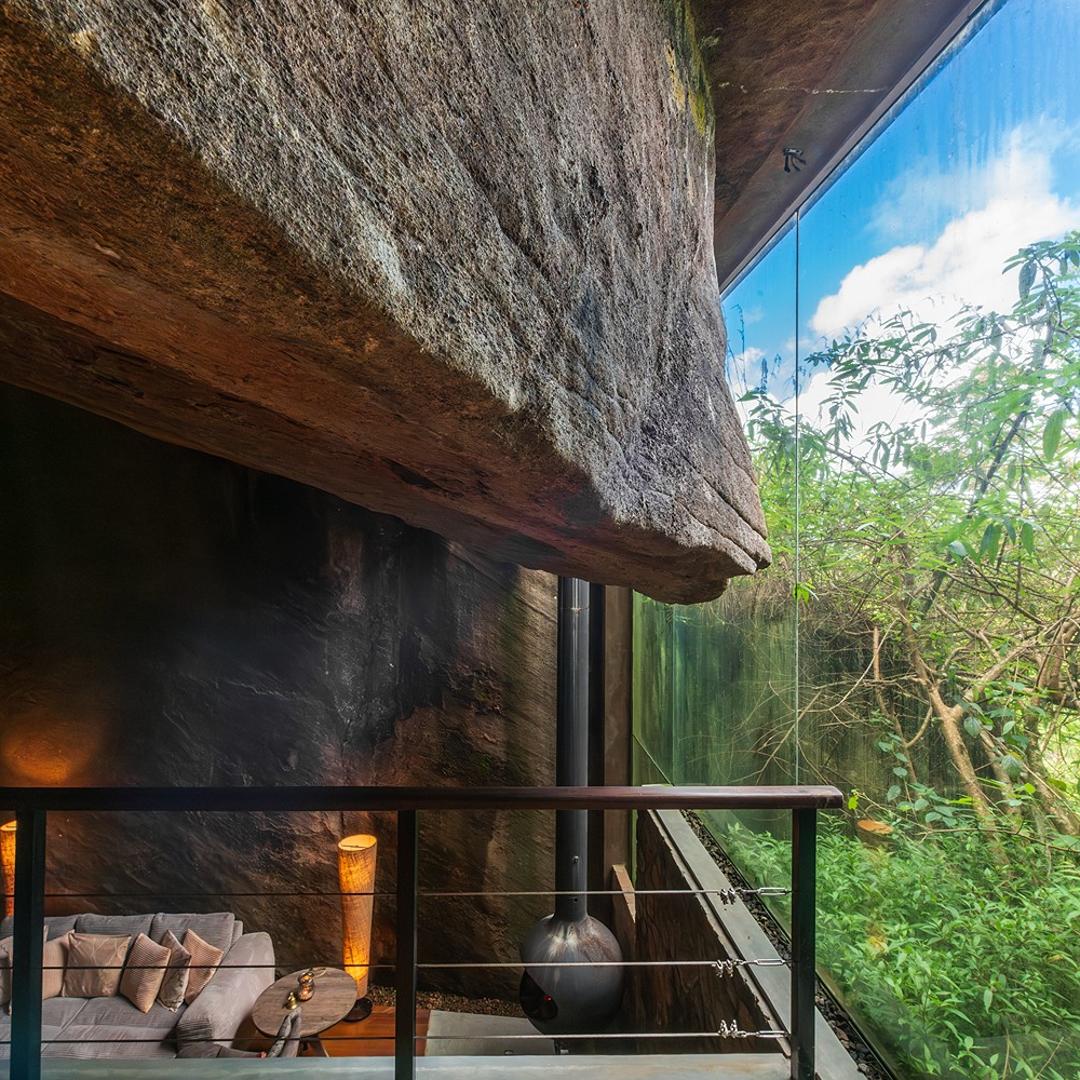 Floor-to-ceiling feature window framing natural rock at The Cavern, Agarapathana