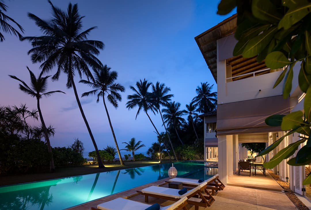 Sri Villas Induruwa pool and palm trees illuminated at dusk, Induruwa Sri Lanka