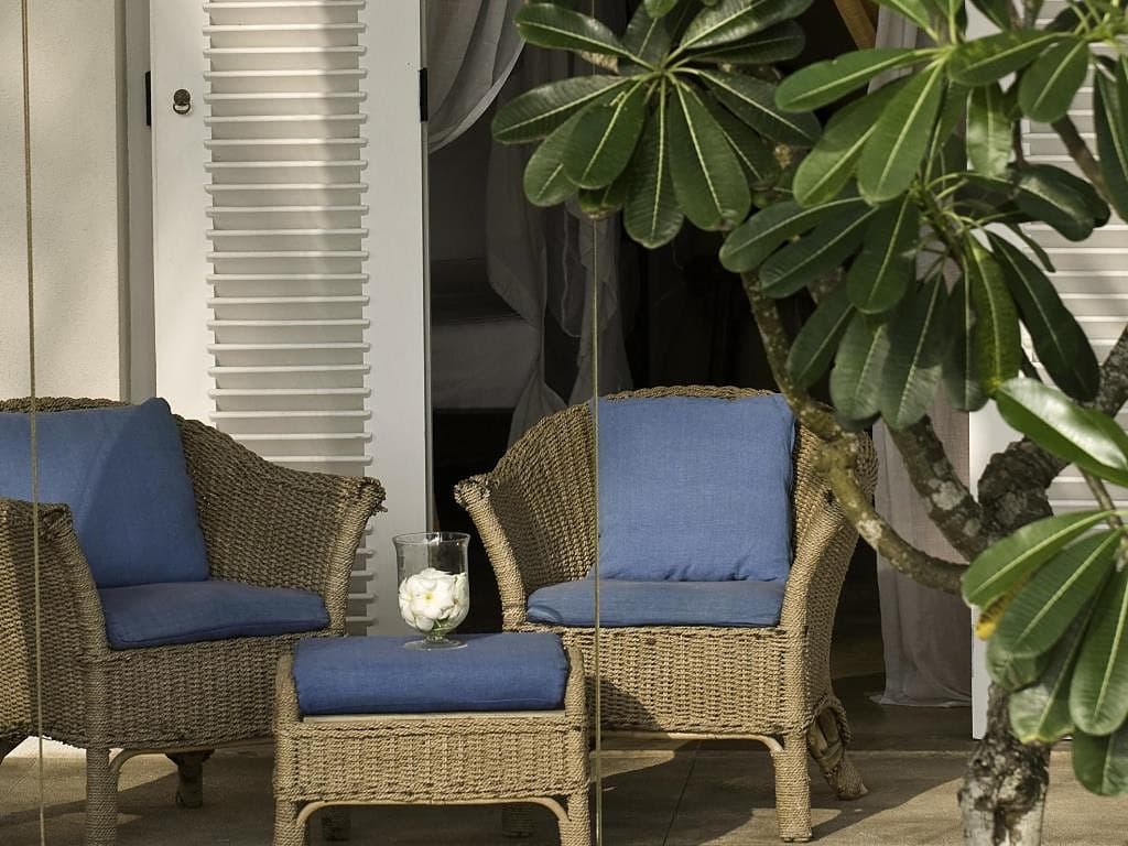 Garden suite private patio with wicker chairs set in lush tropical garden