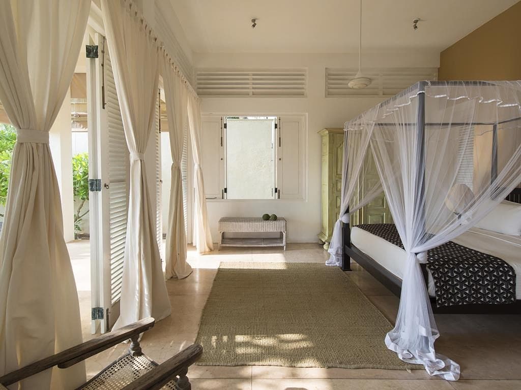 Garden suite with a four-poster bed, draped canopy and wooden flooring in Induruwa