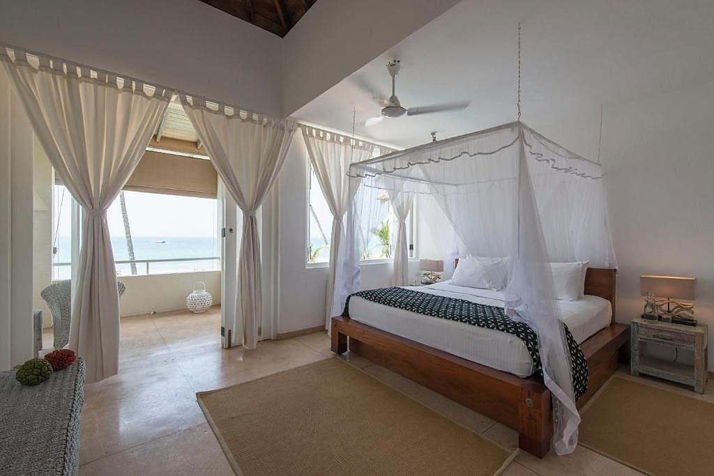 Sri Villas Induruwa sun terrace, infinity pool and palm trees in bright daylight