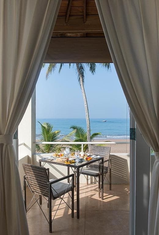 Villa sitting area with draped curtains framing a direct ocean view in Induruwa
