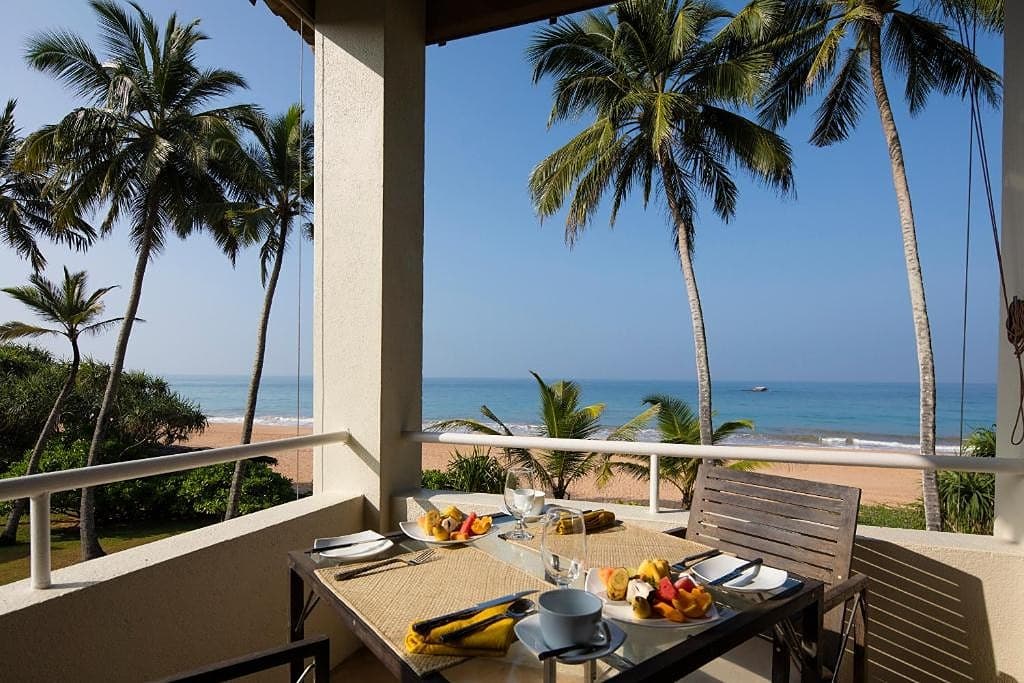 Villa outdoor breakfast table set by the pool with palm trees and ocean views