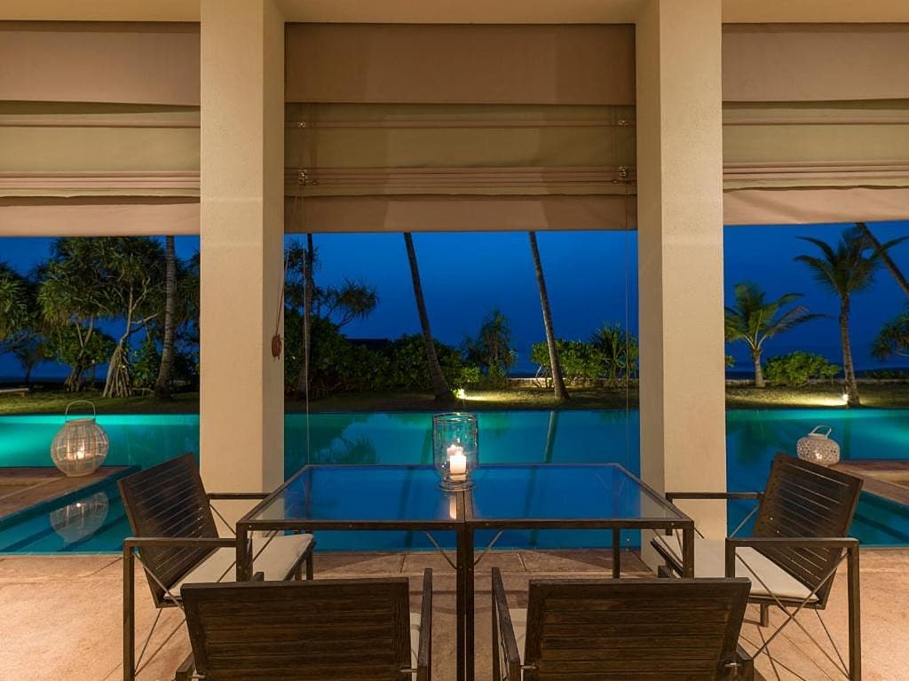 Villa outdoor dining table beside infinity pool with ocean views at Induruwa