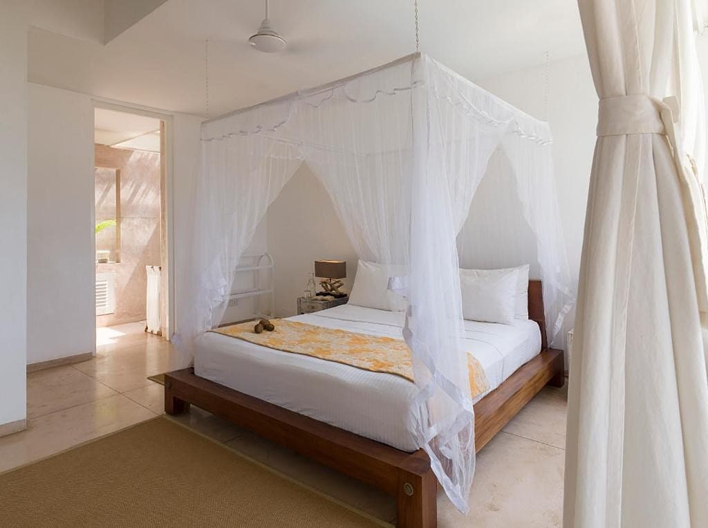 Villa bedroom with white linens, sheer curtains and soft tropical natural light