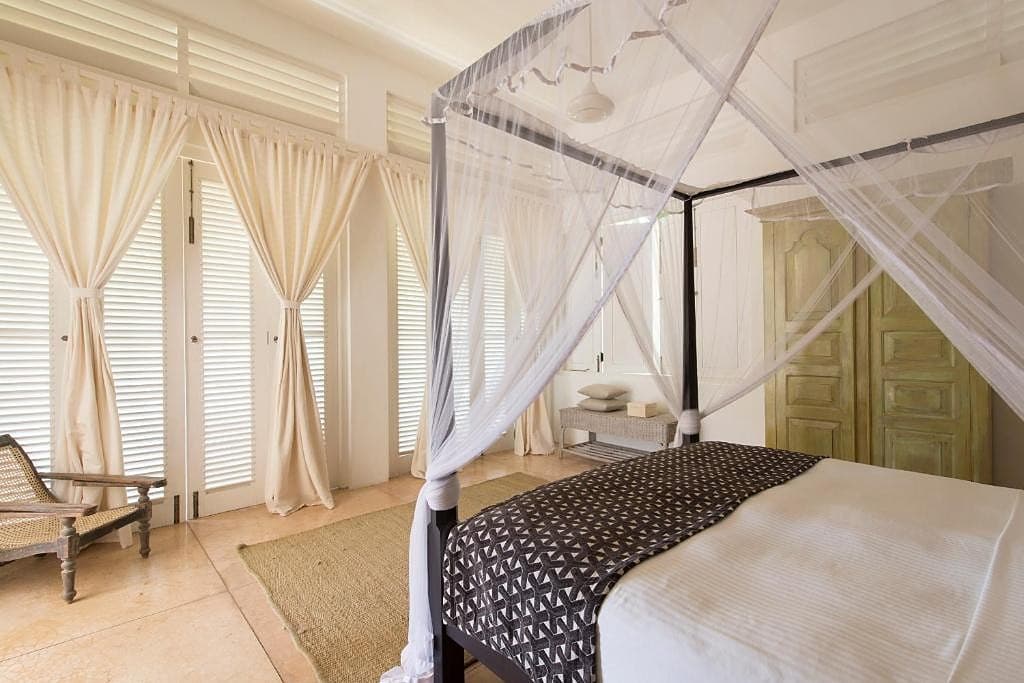 Villa king bedroom with white four-poster bed and fine draped linen canopy