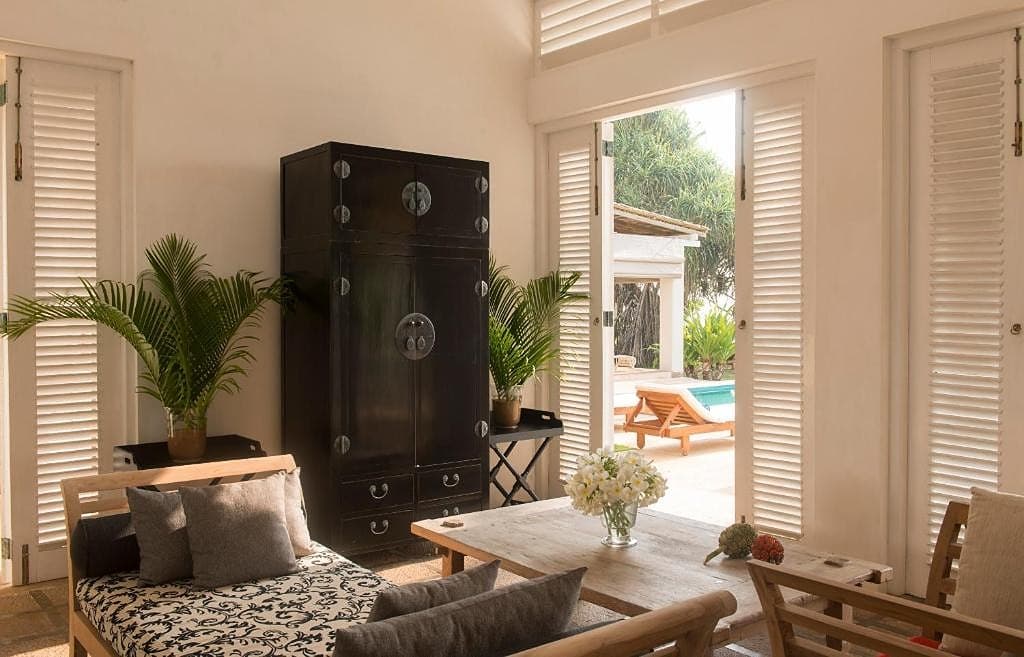 Villa reading nook with wicker armchair and tropical plant decor overlooking the ocean