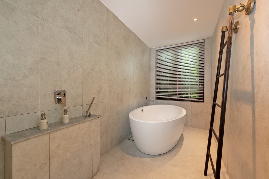 Villa ensuite bathroom with freestanding bathtub and natural stone wall finish