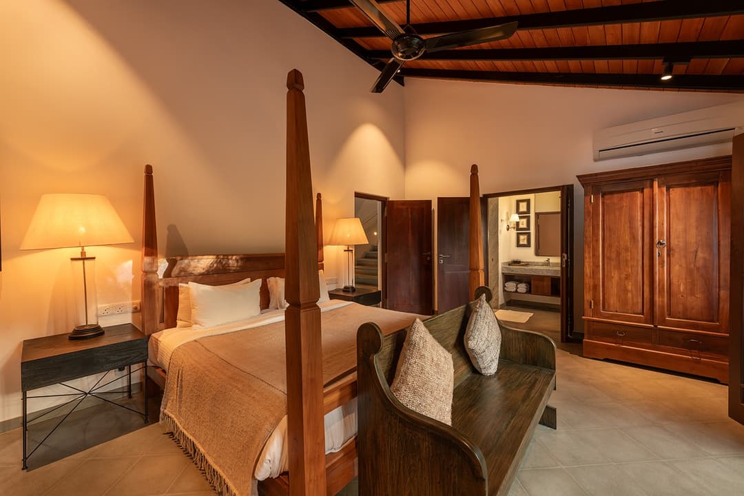 Villa bedroom with four-poster bed, vintage timber furniture and louvred windows