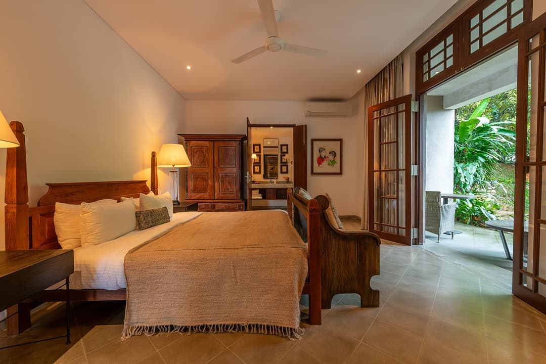 Villa king bedroom with framed artwork, warm lighting and tropical garden view