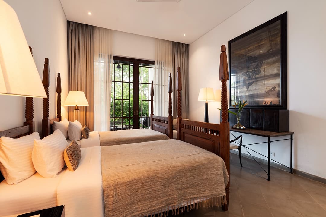 Villa king bedroom with wall-mounted TV, heritage furniture and garden outlook