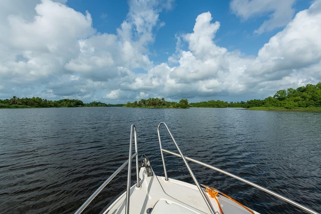 View from boat prow crossing Bolgoda Lake with wide open sky and calm waters