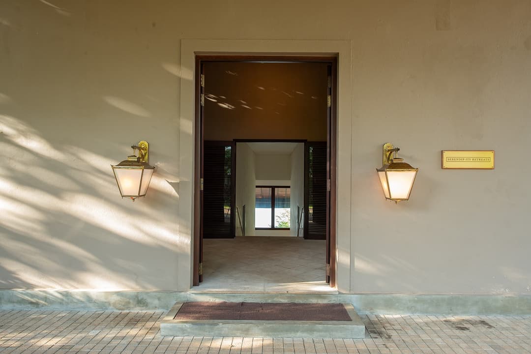 Villa entrance door with warm wall sconces and terracotta facade at evening