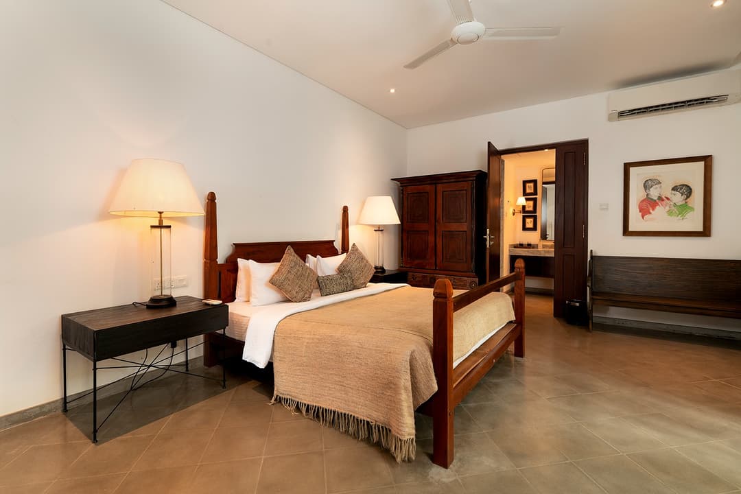 Villa heritage bedroom with dark wood furniture, crisp white linens and garden view