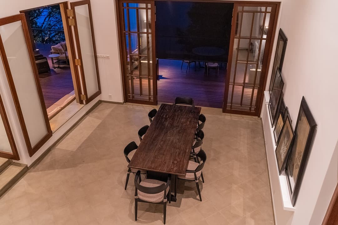 Villa interior dining room with long wooden table and original artwork on walls