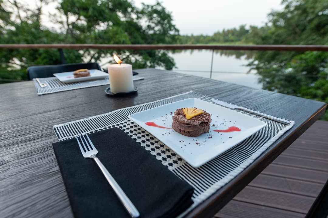 Candlelit lakeside dinner setting on villa deck overlooking Bolgoda Lake