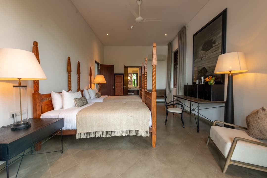 Wide-angle view of villa master bedroom with heritage furniture and soft lighting