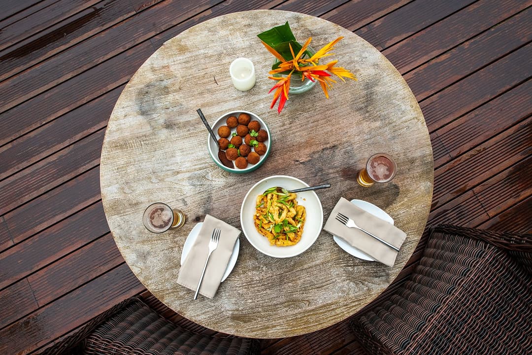 Villa outdoor round table set with Sri Lankan dishes on a timber lakeside deck