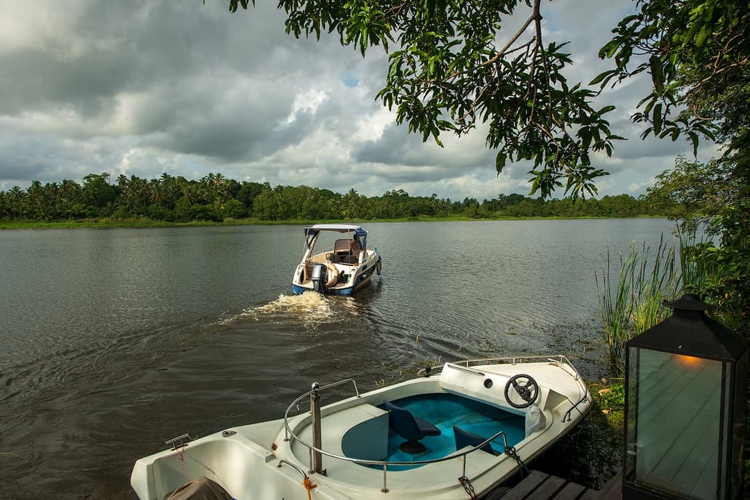 Bolgoda Lake villa private jetty with speedboat and tropical tree canopy