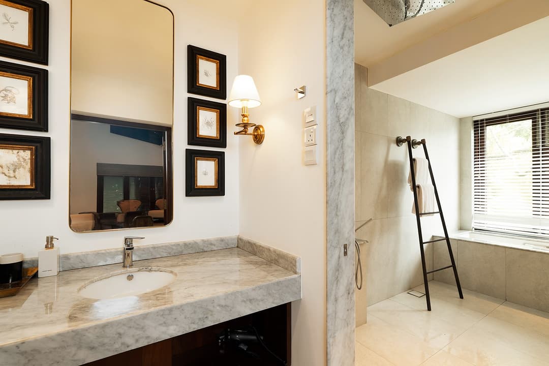 Villa bathroom with stone basin, rain shower and natural stone wall tiles