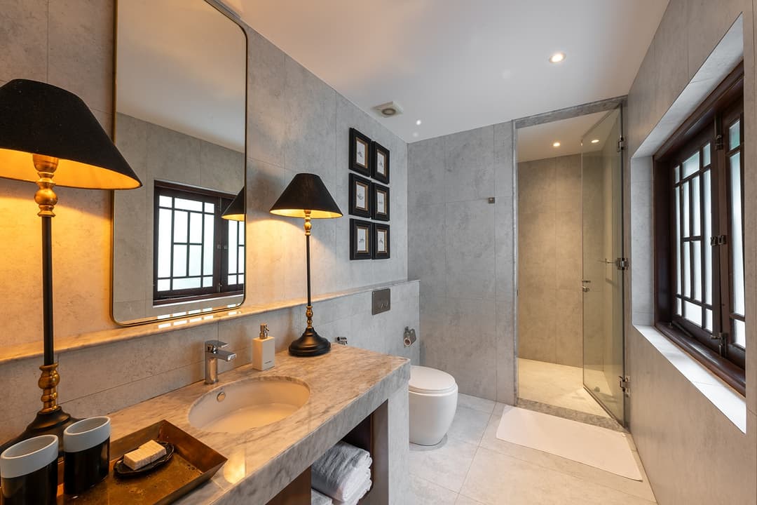 Villa bathroom with natural stone walls, pendant lighting and freestanding basin