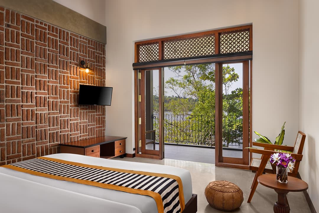 Villa bedroom with exposed brick feature wall and tropical garden views