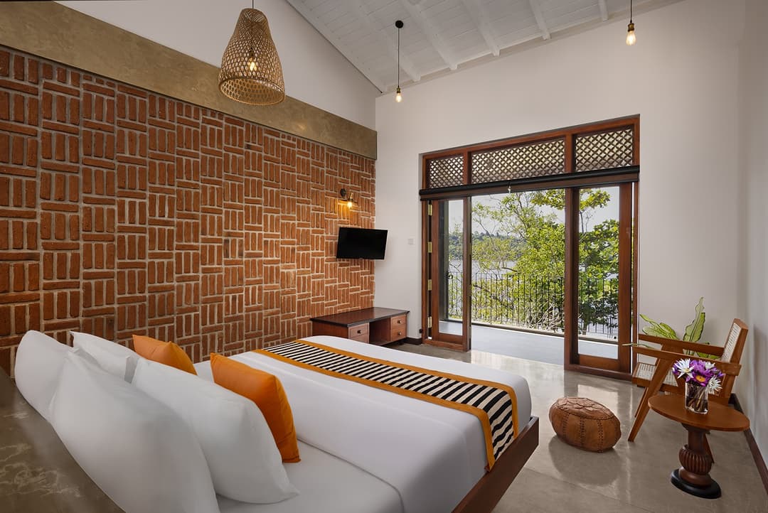 Villa king bedroom with exposed brick wall, timber furniture and garden access