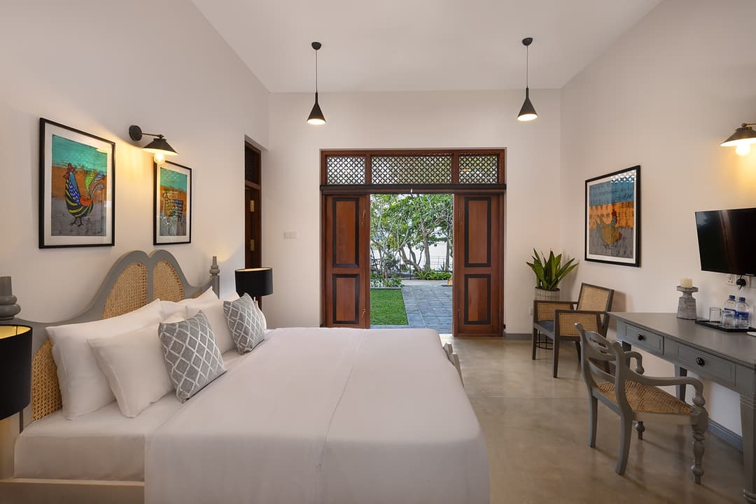 Villa bedroom with framed wall art, louvred timber doors and garden beyond
