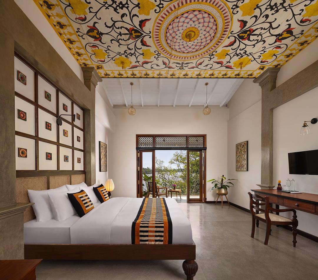 Villa king bedroom with timber doors open to tropical garden in Bentota