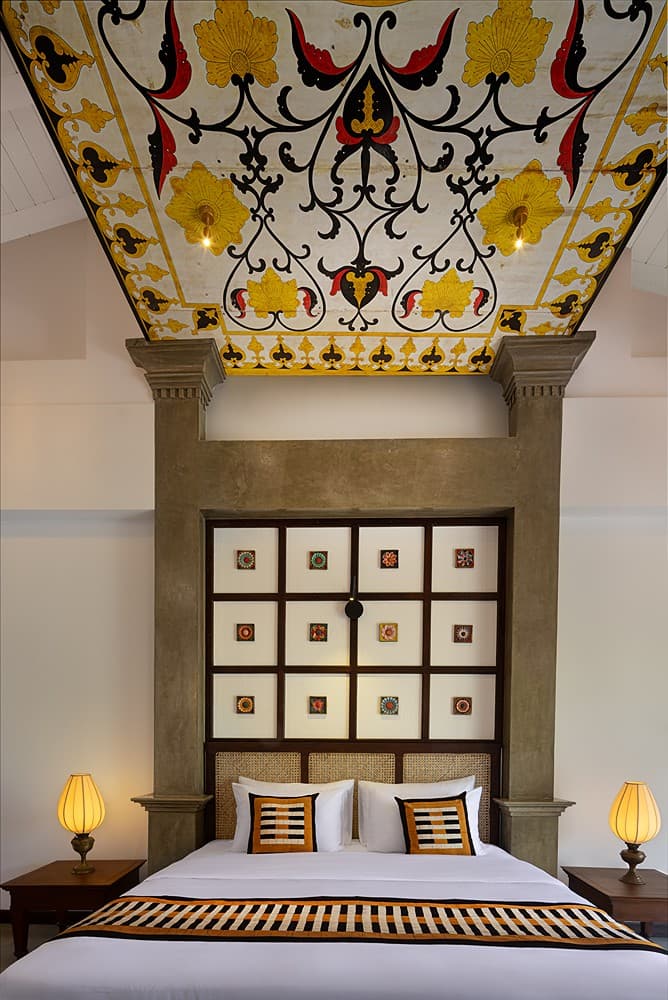 Luxury villa bedroom with ornately painted ceiling and framed wall art in Bentota