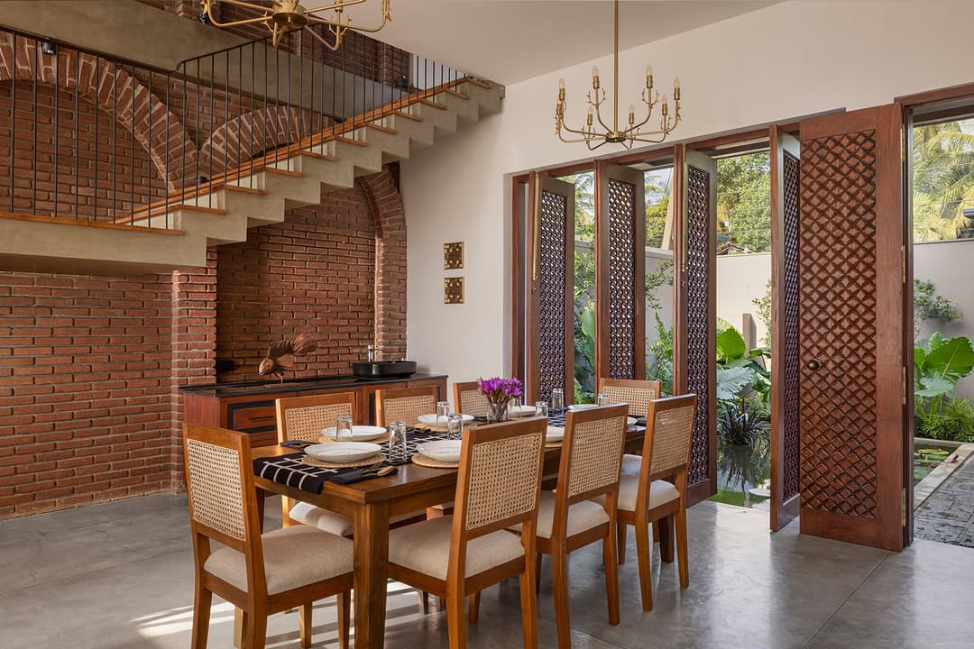 Villa dining room with exposed brick wall, chandelier and arched openings