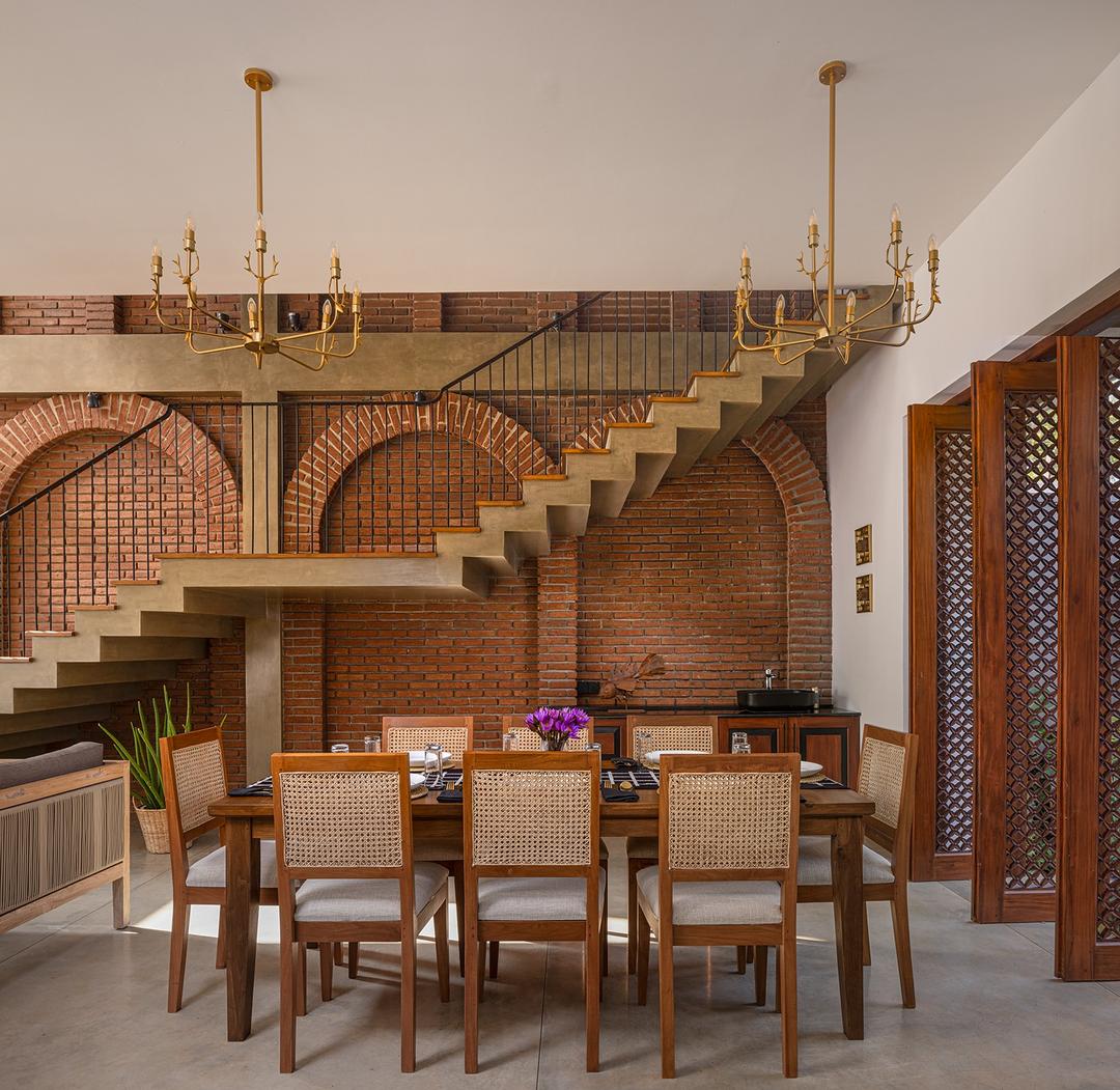 Villa dining room with brass chandelier, arched staircase and timber furniture