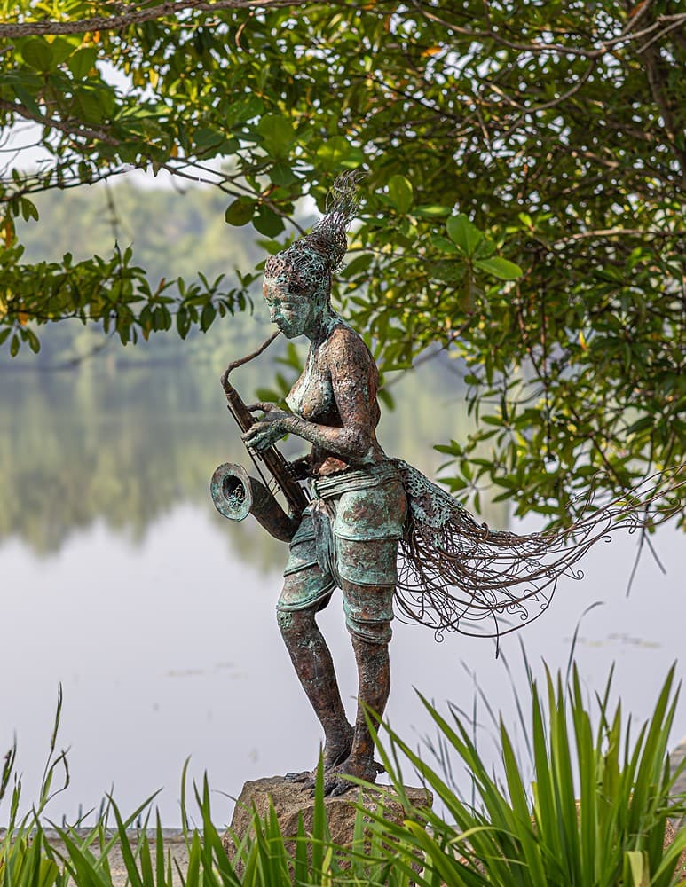 Villa garden with bronze sculpture, tropical plants and decorative pond