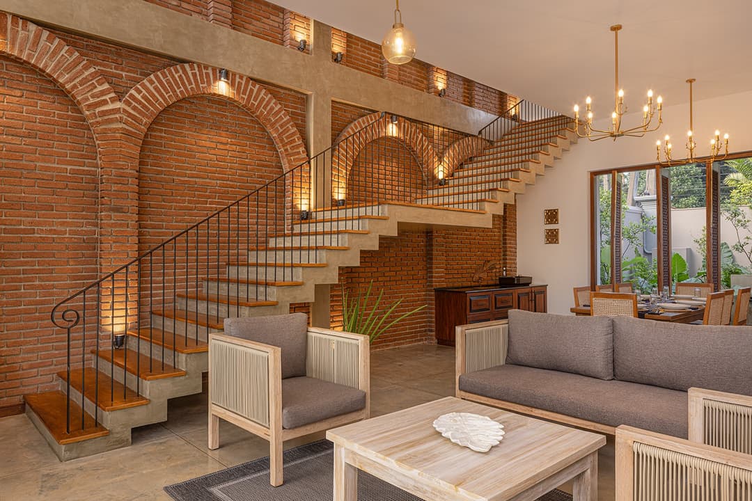 Villa interior with grand staircase, brass chandelier and brick arched openings