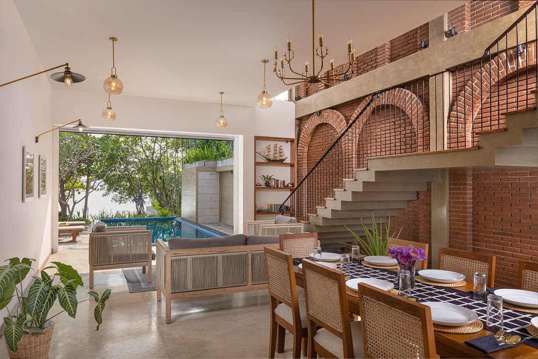 Villa interior staircase with chandelier and pool view through arched openings