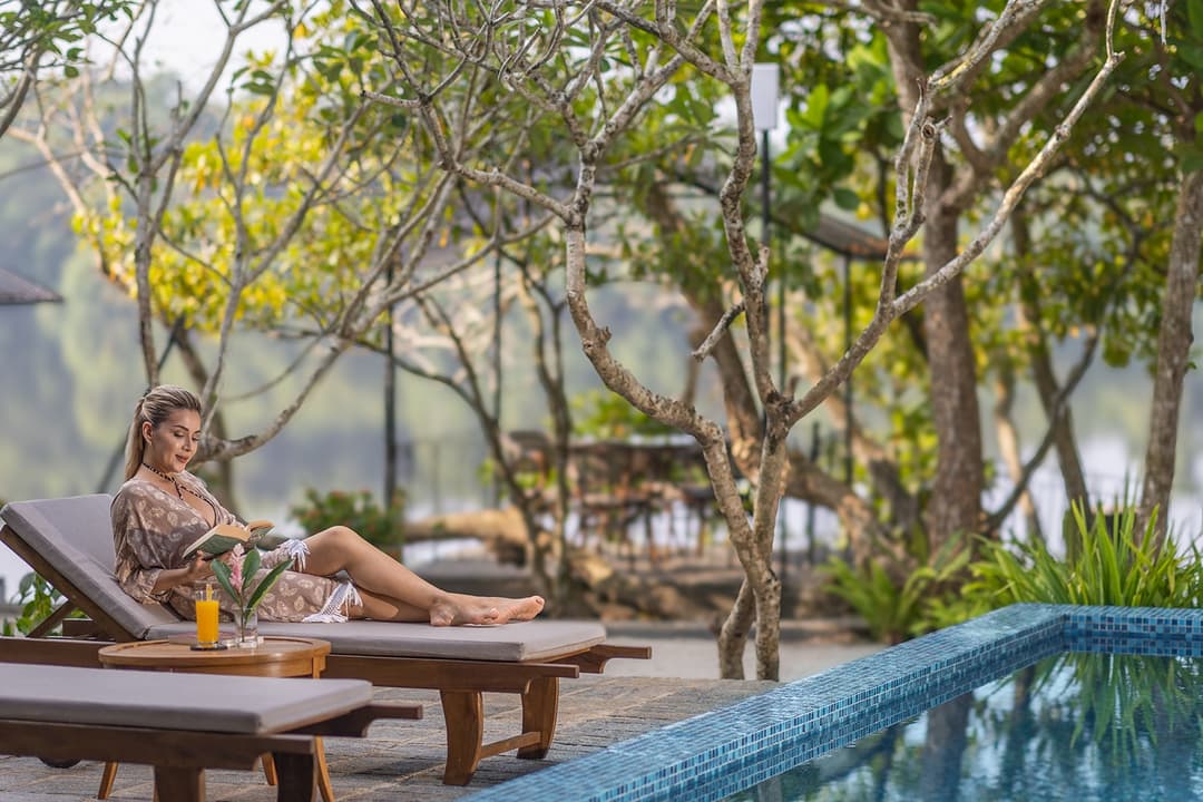 Woman relaxing by villa pool with tropical garden backdrop in Bentota