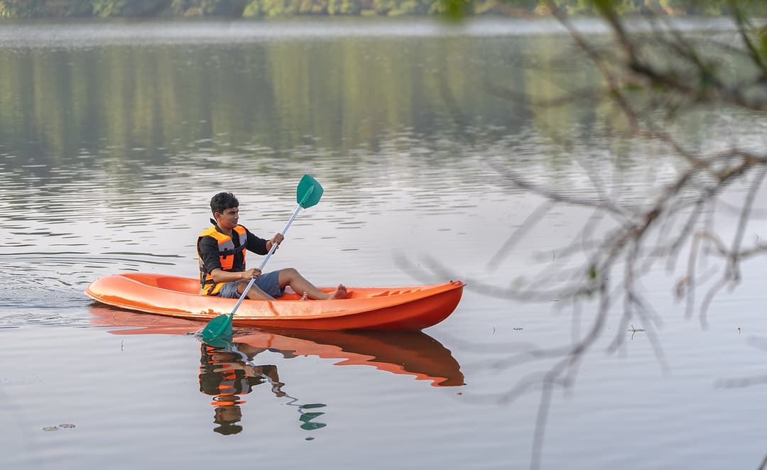 Man kayaking on Dedduwa Lake in a red kayak surrounded by tropical trees