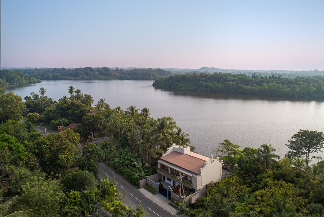 Aerial view of Yahva Bentota villa nestled among trees on Dedduwa Lake at sunset