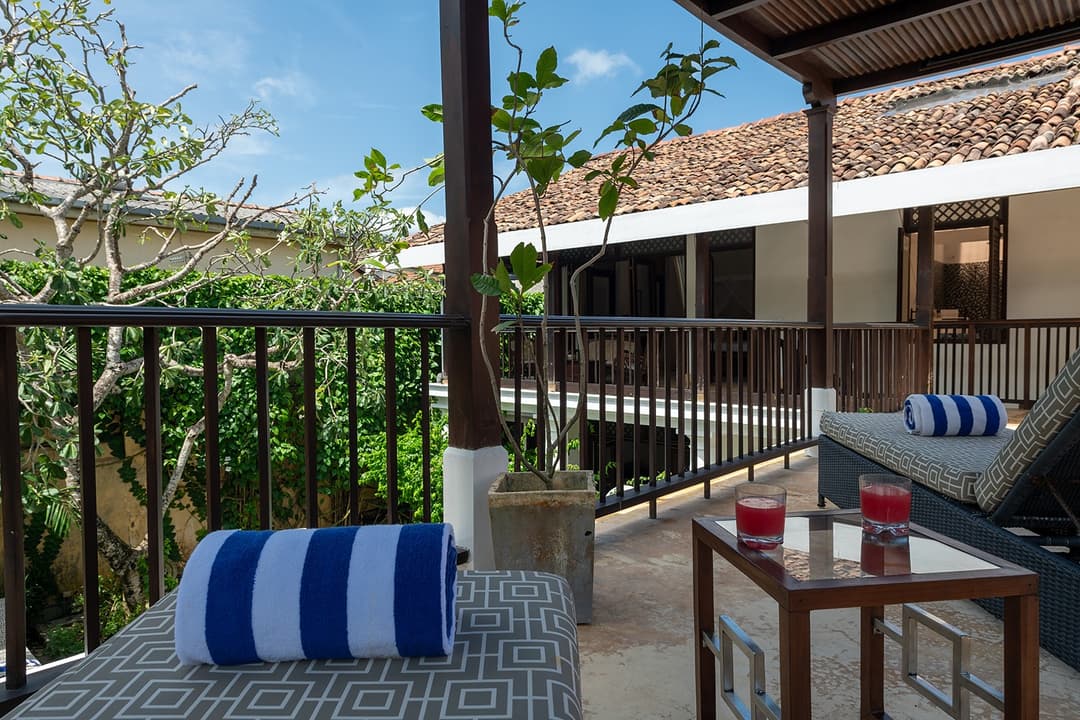 Villa balcony with blue stripe cushions overlooking private pool inside Galle Fort