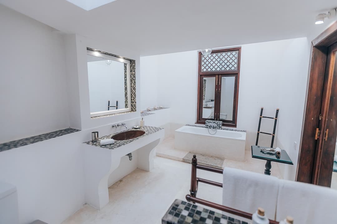 Villa bathroom with white freestanding bathtub and dark timber door in Galle Fort