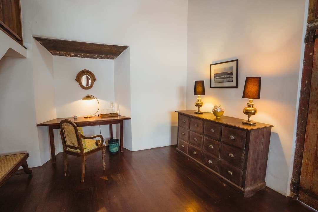 Villa bedroom with antique dresser, mirror and table lamp in colonial Galle Fort villa