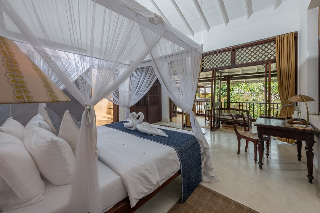 Villa bedroom with mosquito-net four-poster bed and colonial timber windows in Galle Fort