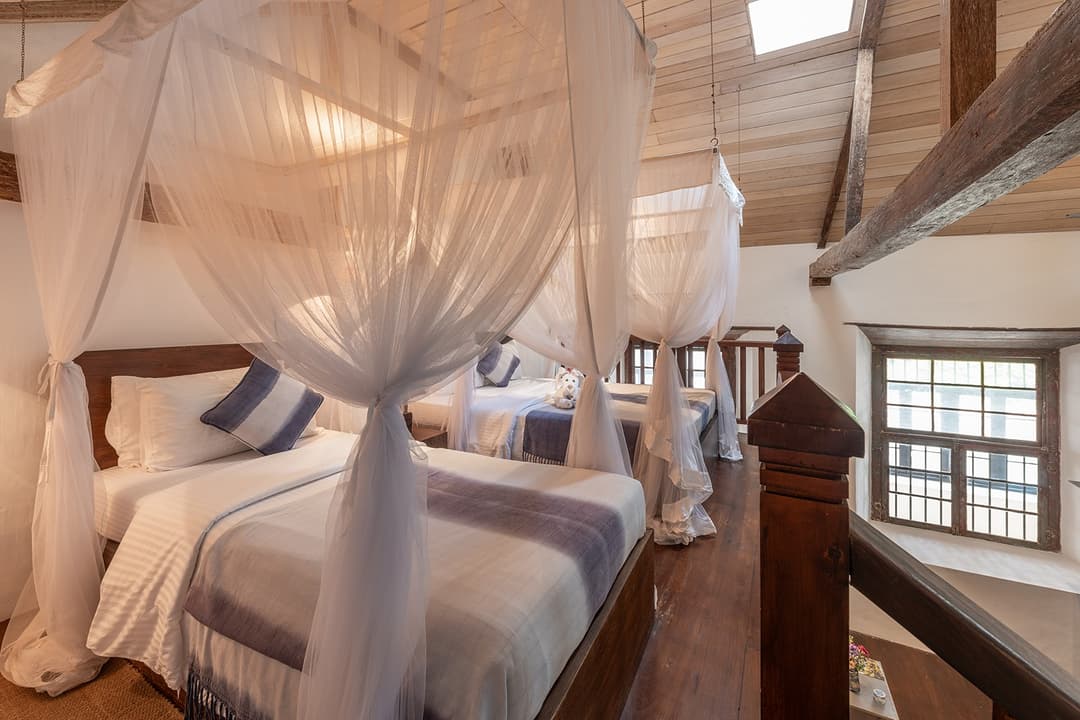 Villa four-poster bedroom on mezzanine level with canopy and colonial views