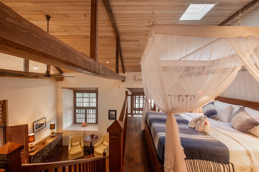 Villa four-poster bedroom with canopy under pitched timber roof in Galle Fort